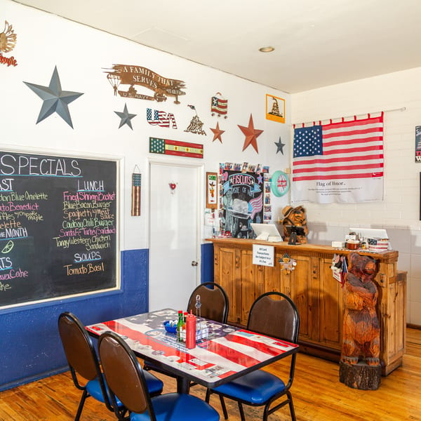 A restaurant dining area with patriotic decor, a specials chalkboard, and an American flag table.